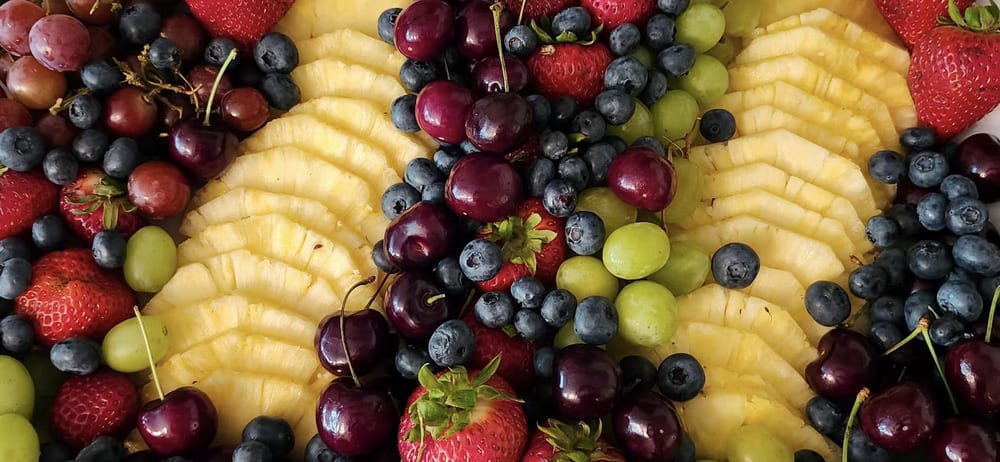 Close-up of fresh berries, grapes and pineapple