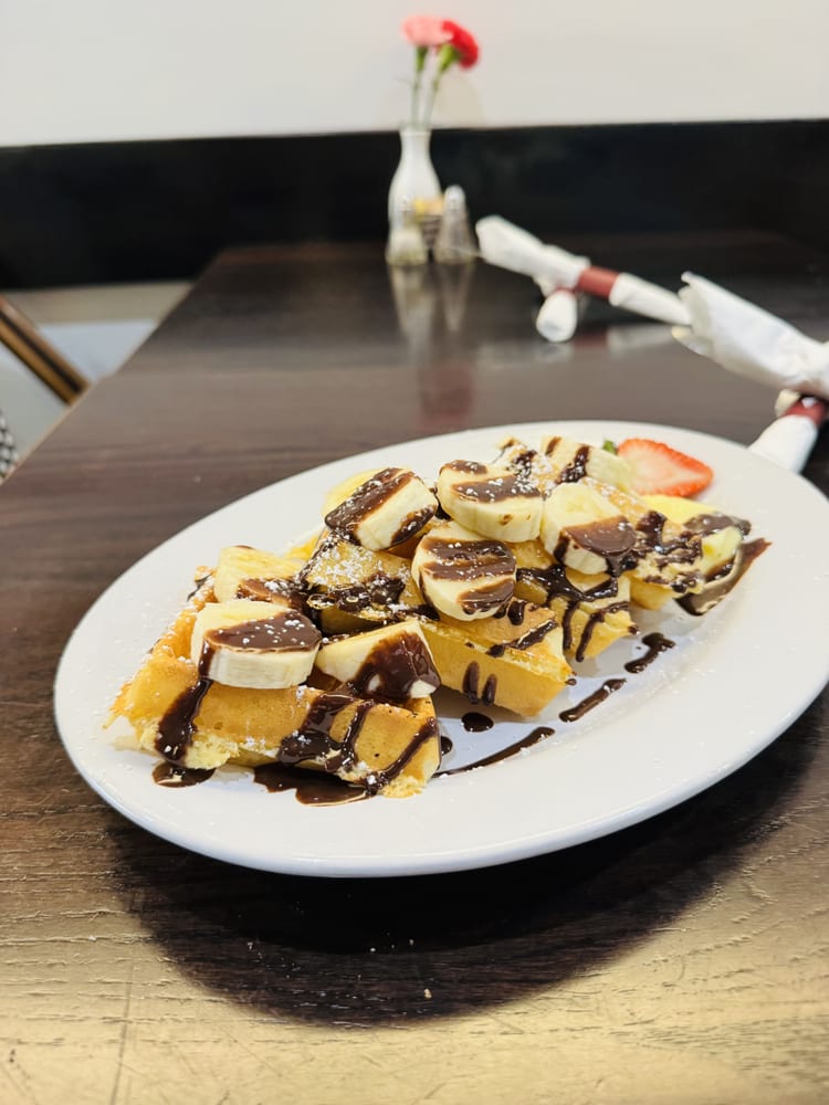 Waffle topped with banana slices and chocolate drizzle
